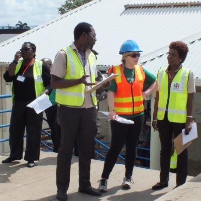A group of Projects Abroad International Development Interns standing outside a building coordinating a plan during Disaster Management work experience in Jamaica. Disaster Management Interns developing plans outside during their International Development Placement in Jamaica.